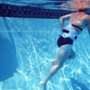 Man in pool in black swimsuit and wearing AquaJogger® Belt demonstrating Aqua Hitch.