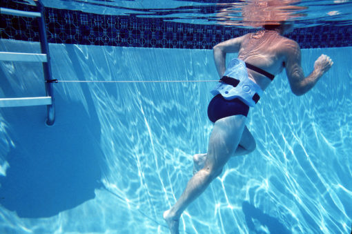 Man in pool in black swimsuit and wearing AquaJogger® Belt demonstrating Aqua Hitch.